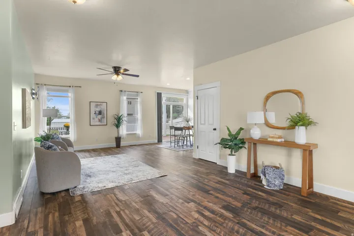 Wood-finish flooring throughout, a ceiling fan with integrated lighting, and multiple windows with white trim