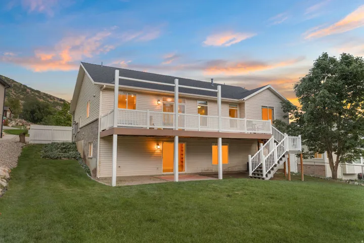 Two-story residence with a composite deck, ground-level patio, and extensive lawn