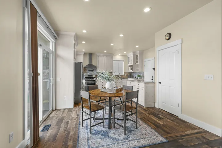 Recessed lighting, wood-finish flooring, white paneled door, sliding glass door, and white cabinetry