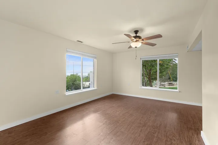 Wood-finish flooring, recessed ceiling fan, and multiple windows providing natural illumination