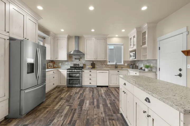 Gourmet kitchen featuring a stainless steel French door refrigerator, white cabinetry, wood-finish flooring, a stainless steel range with double ovens, and recessed lighting