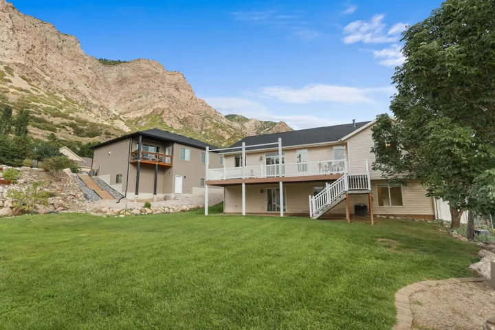 Expansive backyard featuring a manicured lawn, multi-level deck, and mountain backdrop