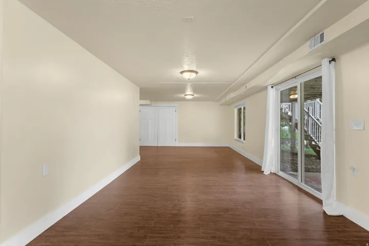 Spacious room with wood-finish flooring, recessed lighting, and a large sliding glass door