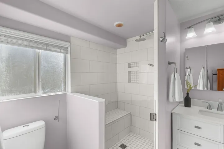 White subway tile shower with a built-in bench, rain shower head, and dual recessed niches