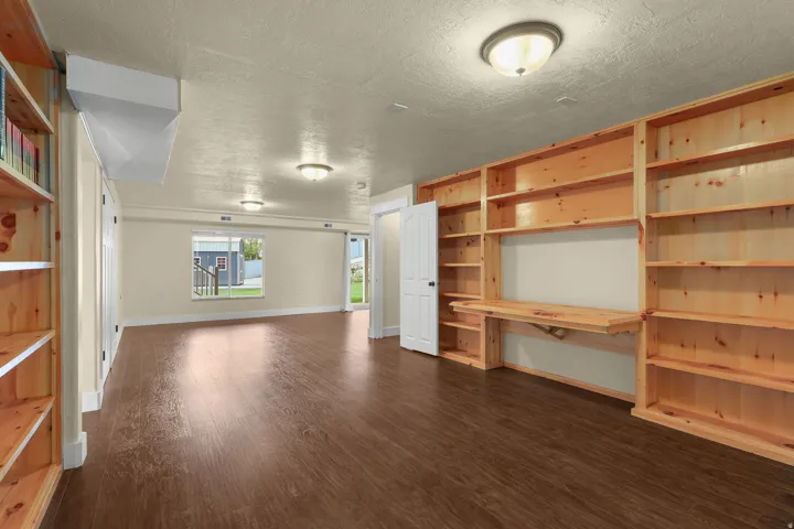 Expansive room featuring wood-finish flooring, built-in shelving, a built-in desk, and multiple ceiling-mounted light fixtures
