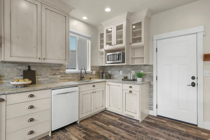 Kitchen featuring light-toned cabinetry, granite-finish countertops, and wood-finish flooring