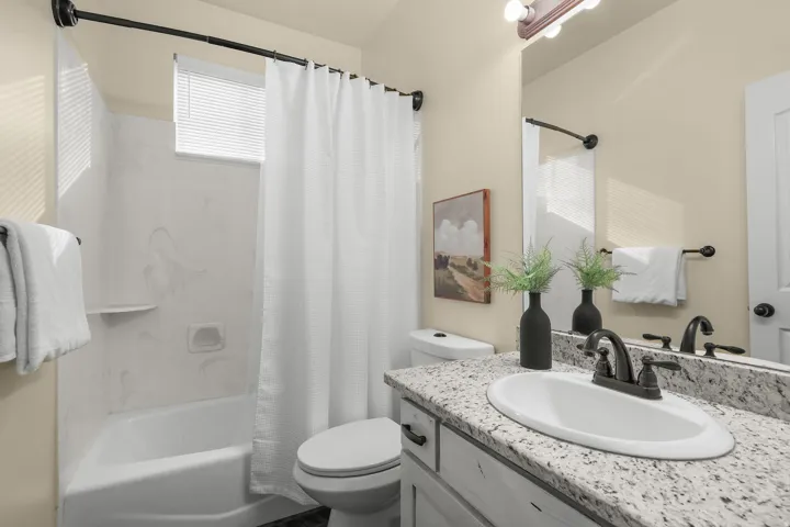 White vanity with a speckled countertop, undermount sink, and dark bronze faucet