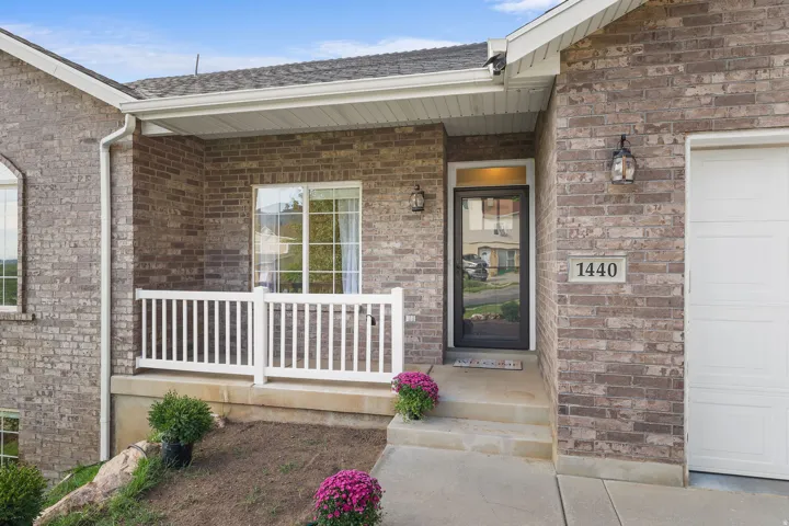 Brick exterior with white garage door, concrete pathway, and covered entry