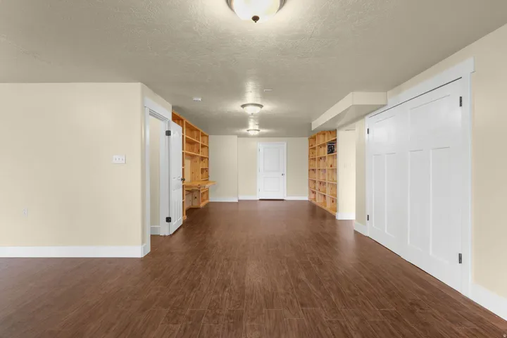 Expansive room featuring wood-finish flooring, recessed lighting, built-in shelving, and white paneled doors