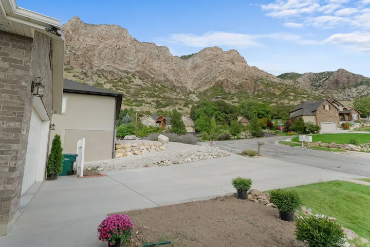 Stone-clad exterior with a two-car garage, concrete driveway, and an expansive mountain backdrop