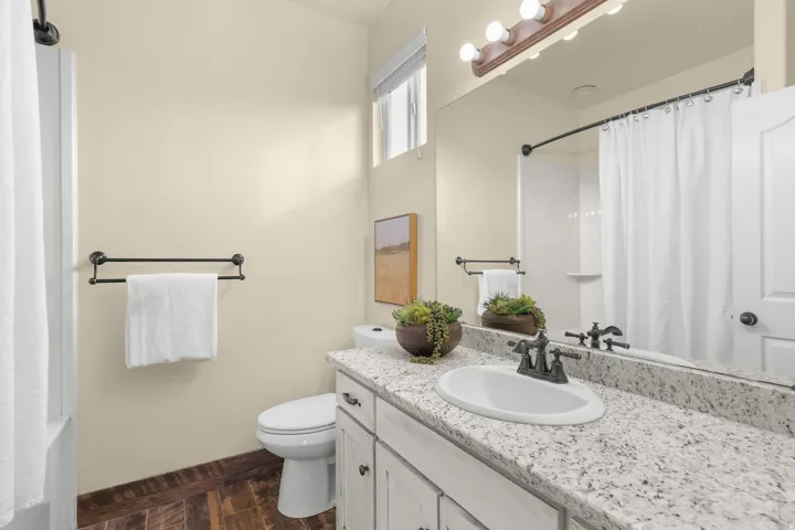 Bathroom featuring a single vanity with stone-finish countertop, undermount sink, and dark-finish faucet