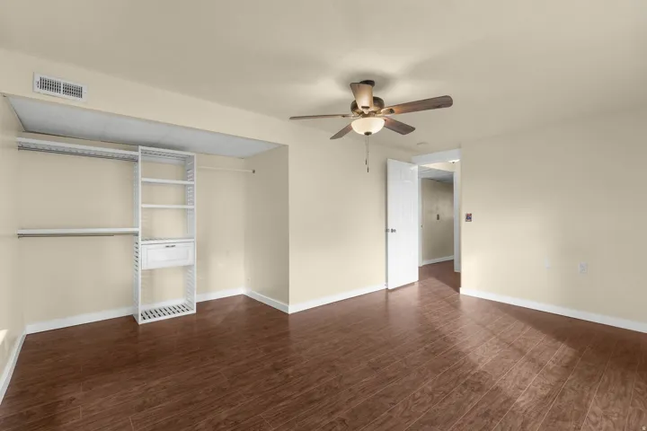 Wood-finish flooring, ceiling fan with integrated lighting, and built-in closet organization system