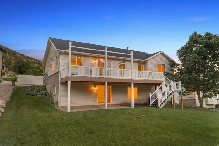 Expansive backyard featuring a manicured lawn, two-story deck with white railings, walkout lower level, and mature landscaping