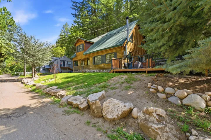 Wood-sided residence with a green metal roof, a wood deck, and natural rock landscaping