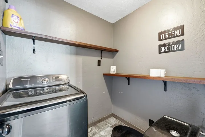 Textured walls with neutral paint, wood-finish open shelving, and patterned flooring