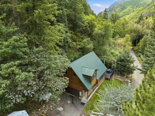 Wood-sided exterior with a green metal roof, attached garage, and a covered porch