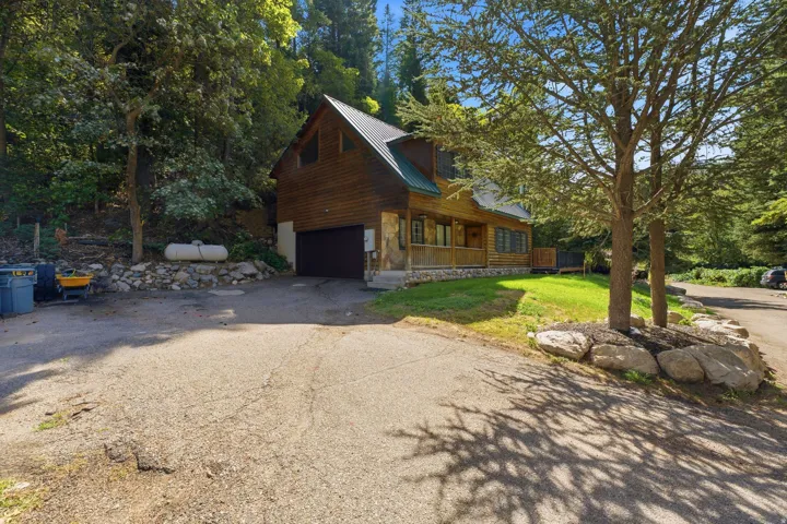 Wood-sided exterior with a metal roof, attached garage, and a covered front porch