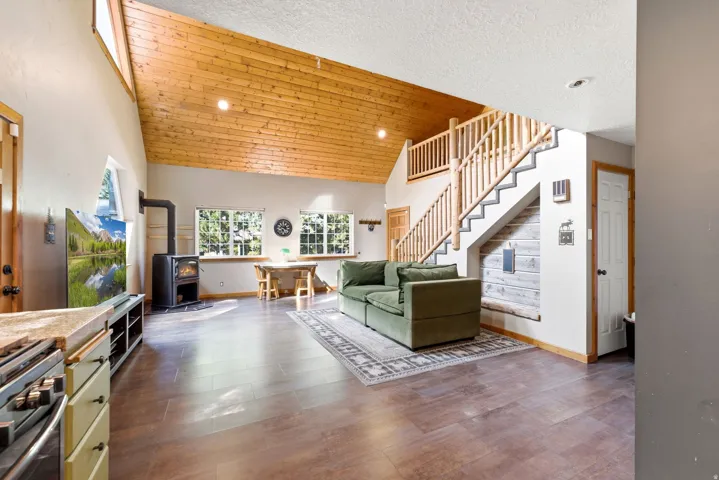 Vaulted wood-paneled ceiling, wood-finish flooring, built-in wood-burning stove, natural wood staircase, and multiple windows