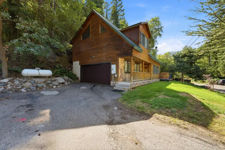 Wood-sided exterior with an A-frame roofline, stone foundation accents, and an attached garage