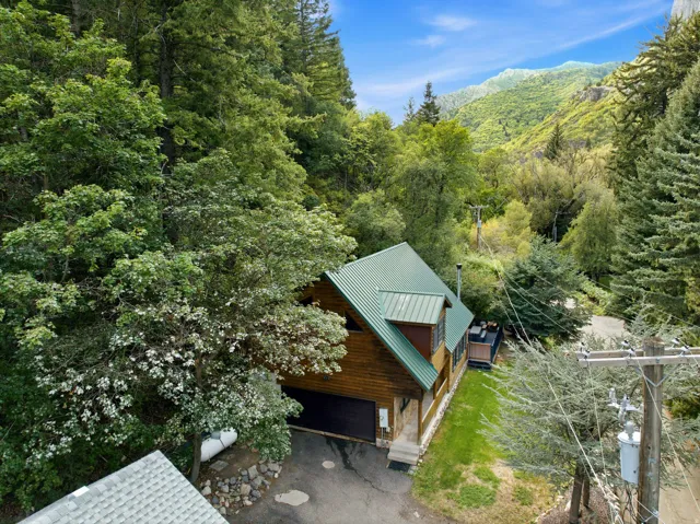 Wood-clad exterior with a green metal roof, attached garage, and stone steps