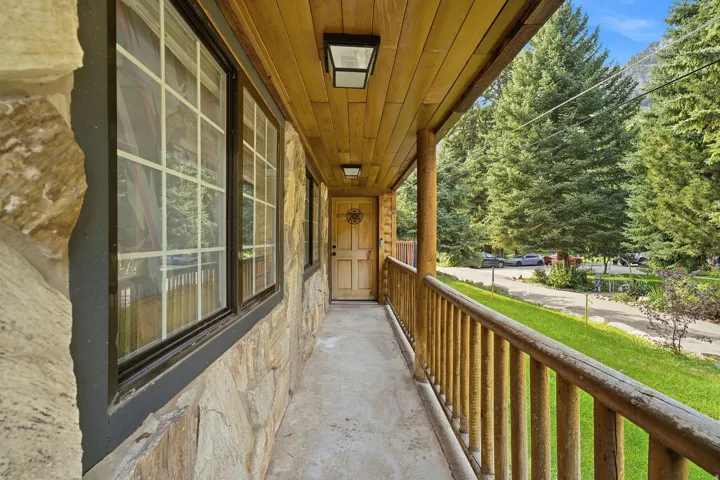 Stone exterior with grid-pattern windows, wood-paneled ceiling, recessed lighting, and a wood railing porch