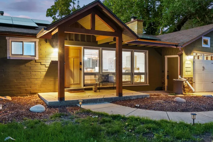 Covered entry with stone-finish patio, wood-finish columns, and a solid wood front door