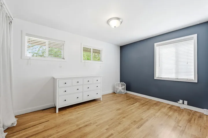 Hardwood-style flooring, white walls, and a single accent wall in a dark tone