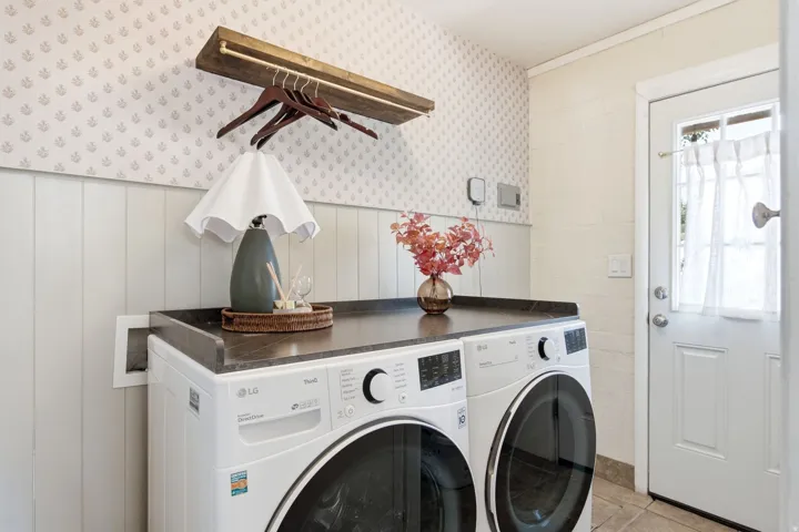 Laundry area featuring a built-in countertop, paneling, and patterned wallpaper