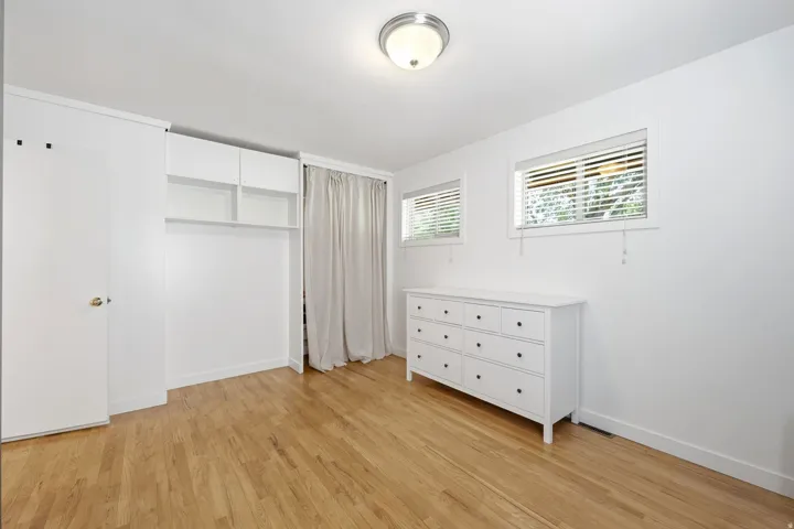 Wood-finish flooring, built-in open shelving, built-in cabinetry, two windows with blinds, and flush mount lighting
