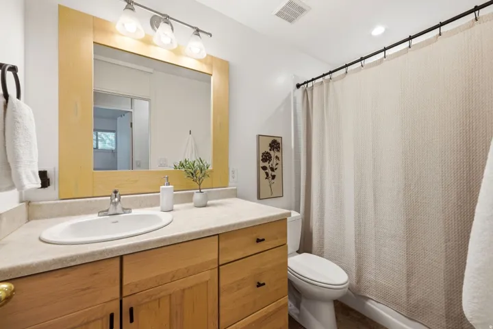 Bathroom featuring a light wood-finish vanity with an integrated sink, a light-toned countertop, and an overhead vanity light fixture