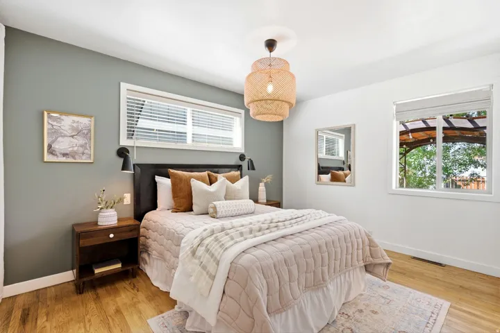 Wood-finish flooring with white baseboards, wall-mounted sconces, and a decorative ceiling light fixture