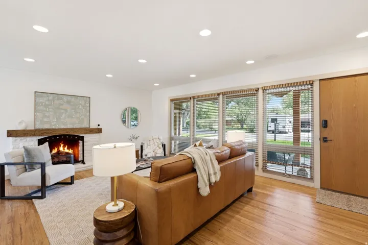 Wood-finish flooring, recessed lighting, and a stone-clad fireplace with a wood mantel