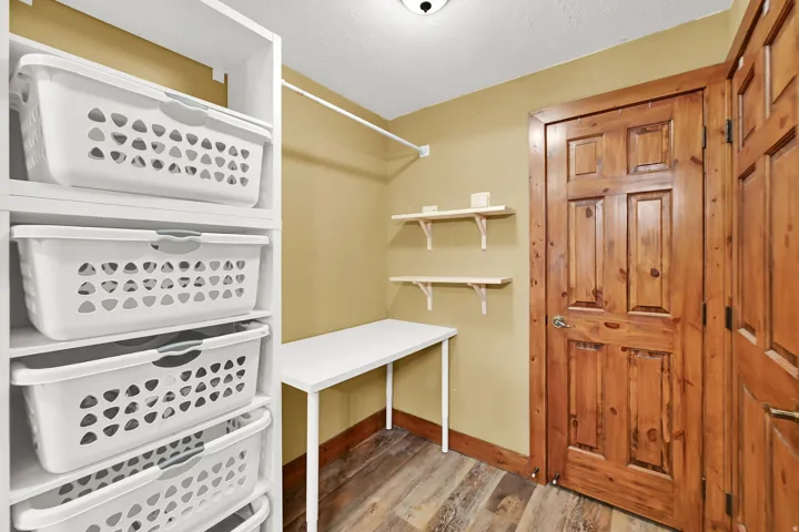 Built-in white shelving, wood-finish flooring, warm-toned wall paint, and natural wood doors