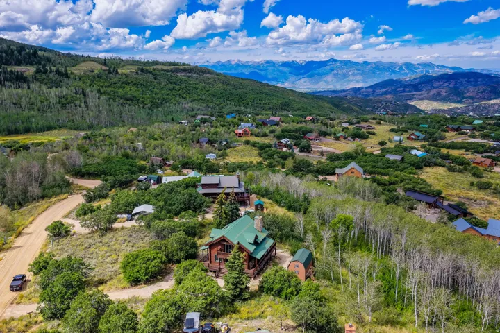 Expansive property featuring a rustic-style residence, a detached auxiliary structure, and a natural landscape with mature trees