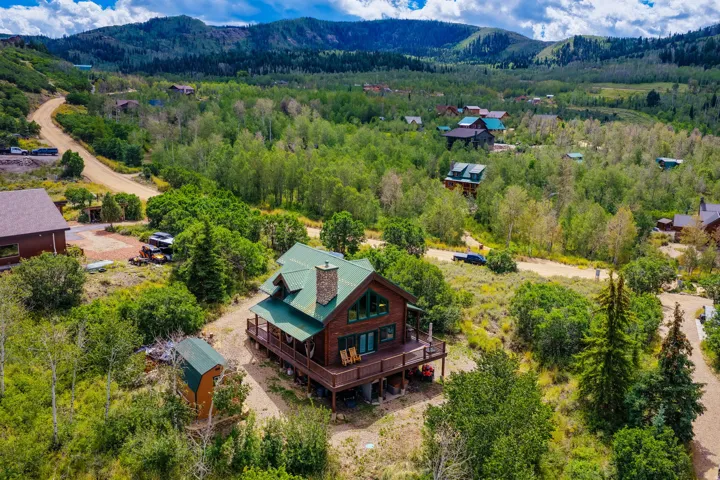 Cabin-style residence with a green metal roof and a stone chimney