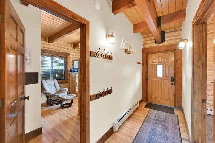 Wood-finish flooring, exposed wood beams, wood-paneled walls, and wood-framed doors