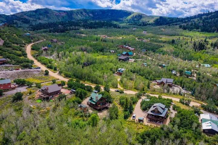 Expansive mountainous terrain with abundant mature trees and multiple residential structures