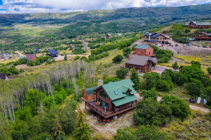 Rustic-style residence featuring a green metal roof, wood siding, and an expansive wrap-around deck