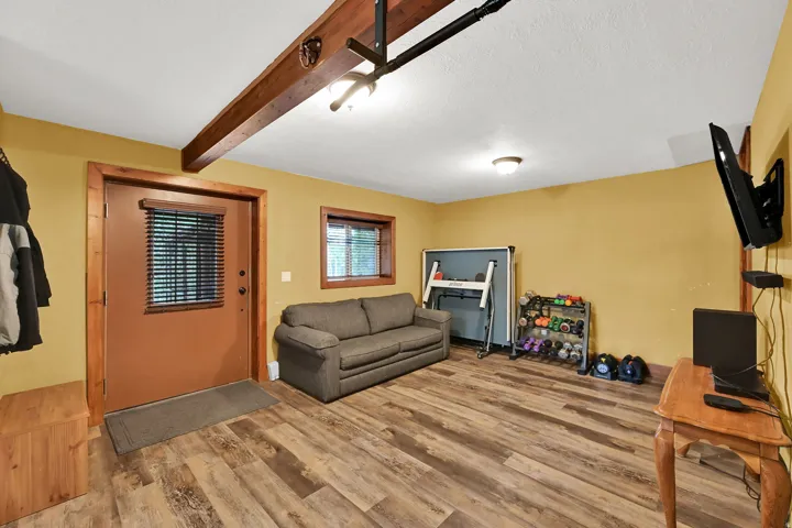 Wood-finish flooring, exposed ceiling beam, recessed lighting, and a window with blinds