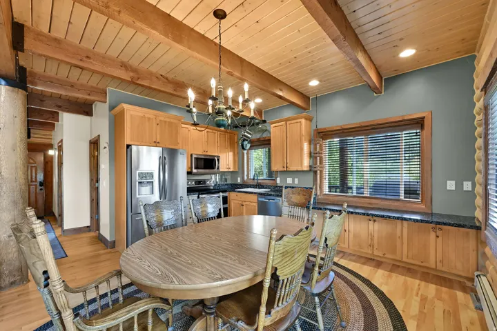 Exposed wood beam ceiling, wood-finish flooring, recessed lighting, and a window with wood trim