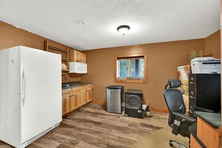 Wood-finish flooring with a built-in cabinetry, an integrated sink, and a window with wood trim