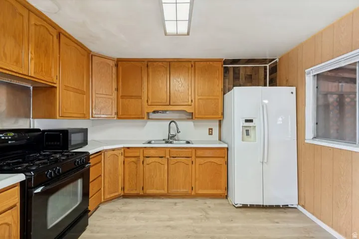 Kitchen featuring wood-finish cabinetry, white countertops, a built-in sink, and wood-finish flooring