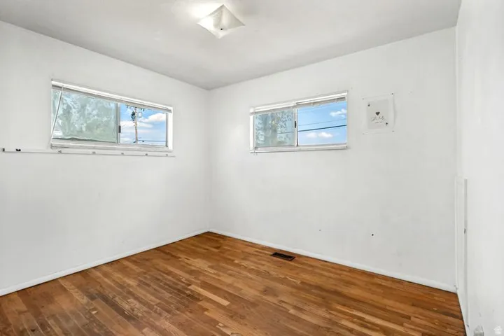 Wood-finish flooring, white walls, and two windows allowing natural light