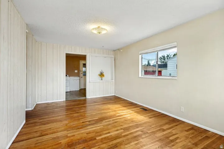 Hardwood flooring, recessed window, ceiling-mounted light fixture, vertical wall paneling, painted drywall