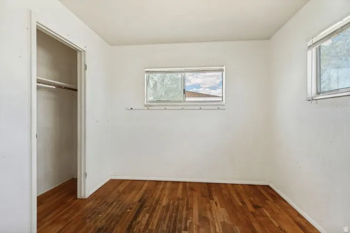 Hardwood flooring throughout, two windows for natural light, and a built-in closet with shelving
