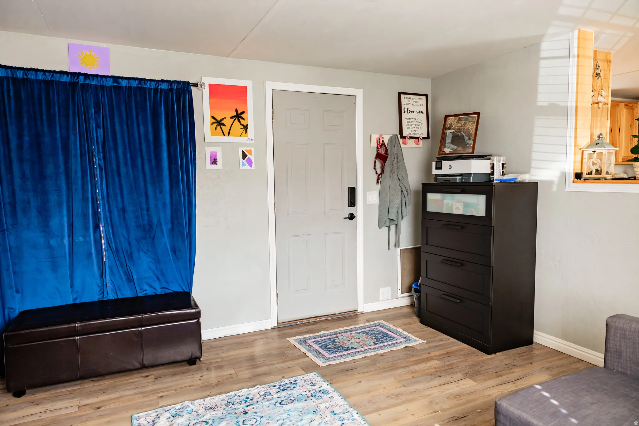 Wood-finish flooring throughout, featuring a neutral wall color and a light-colored entry door