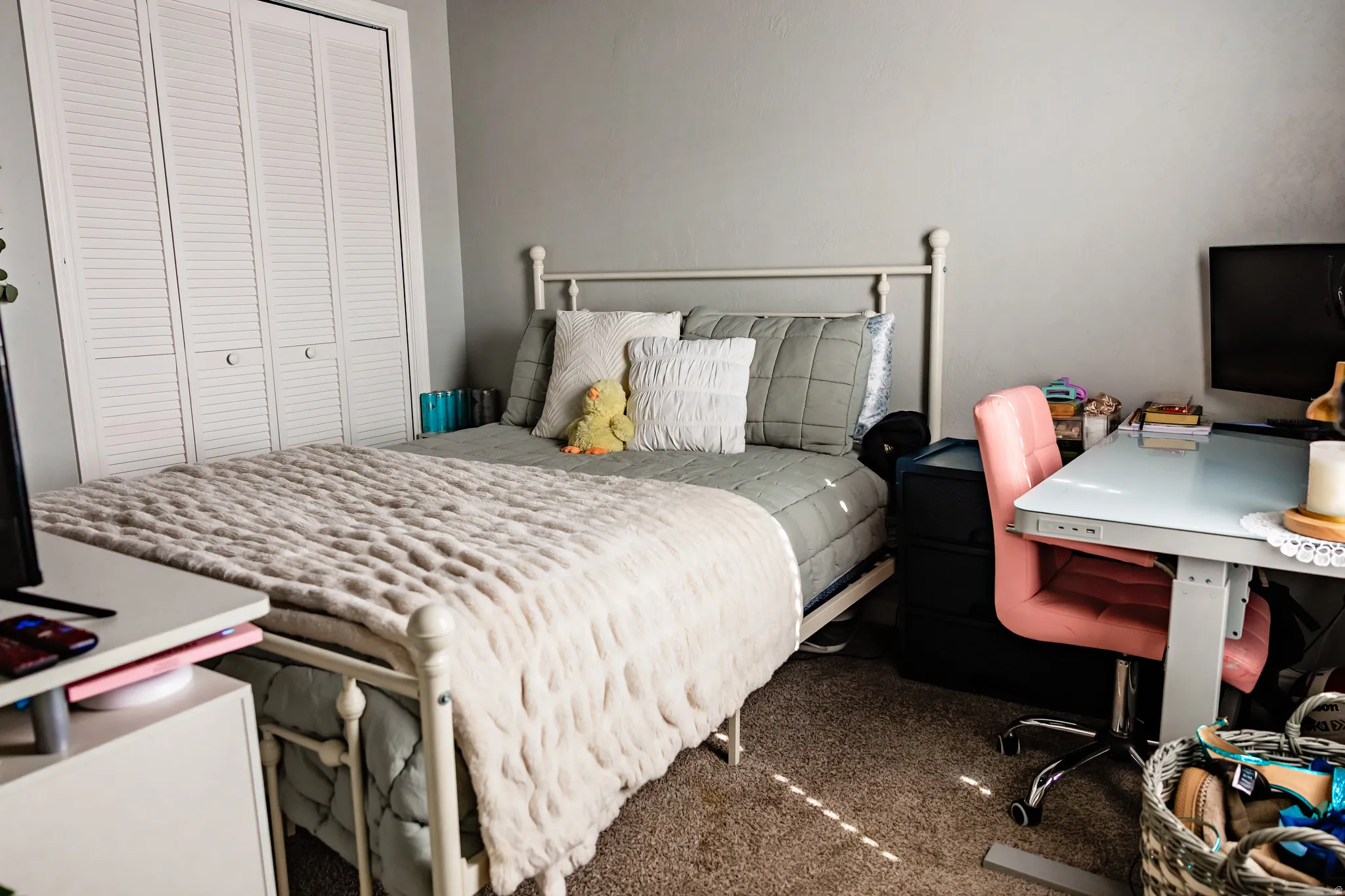 Carpeted flooring, neutral wall color, louvered bi-fold closet doors, and metal bed frame