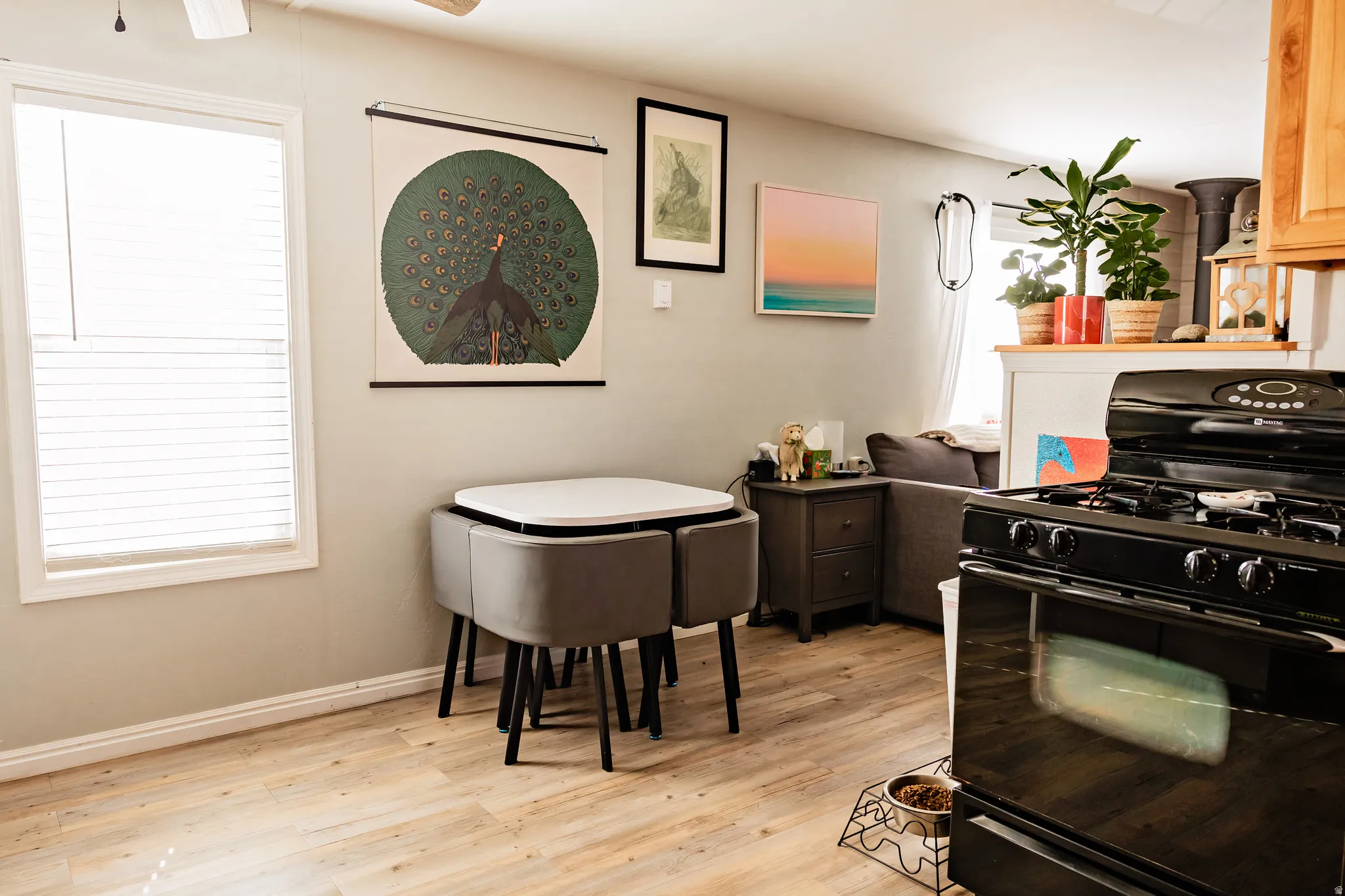 Wood-finish flooring throughout, white trim, window with blinds, ceiling fan, and built-in white shelving