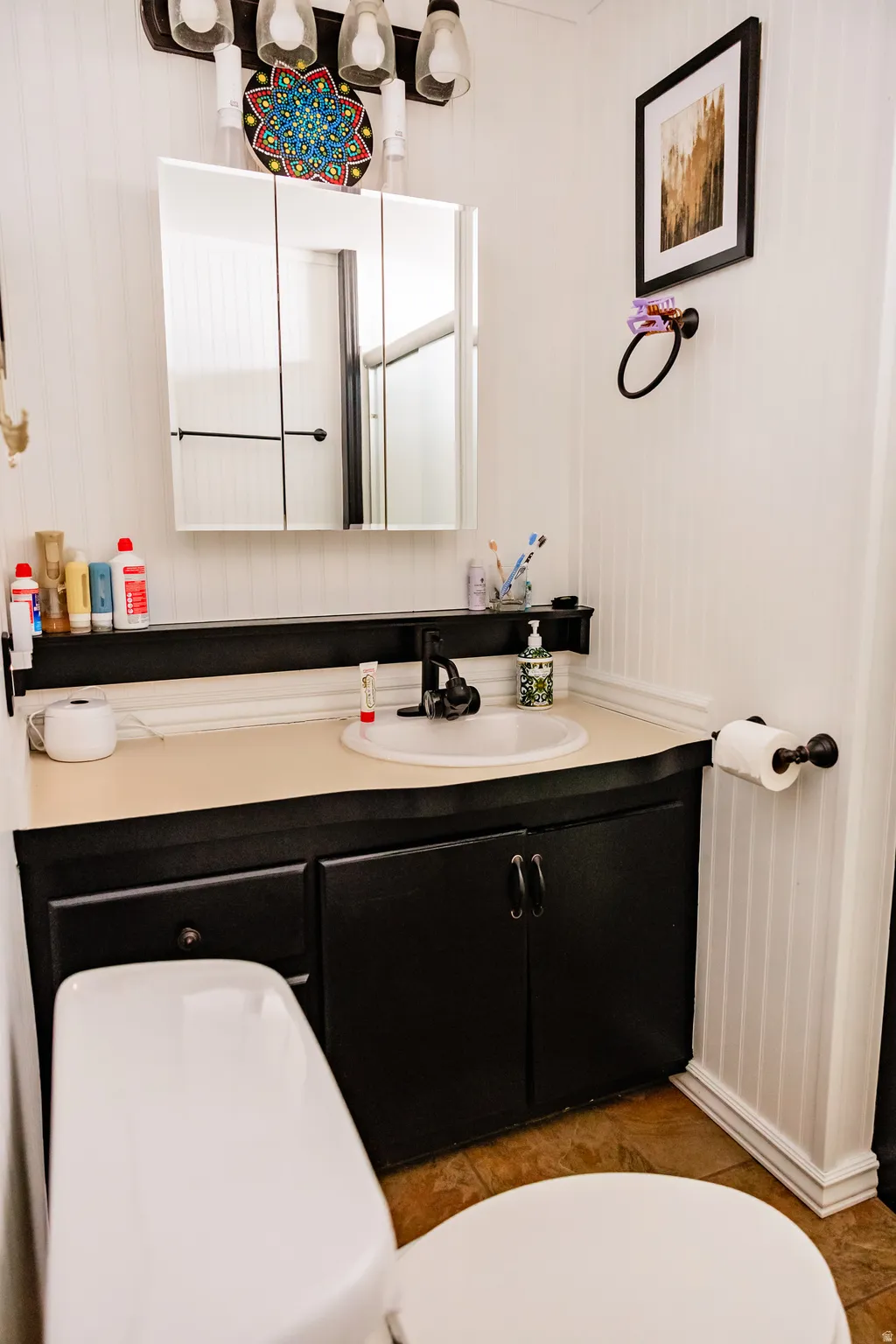 Vanity with an integrated sink, black cabinetry, and a light-toned countertop