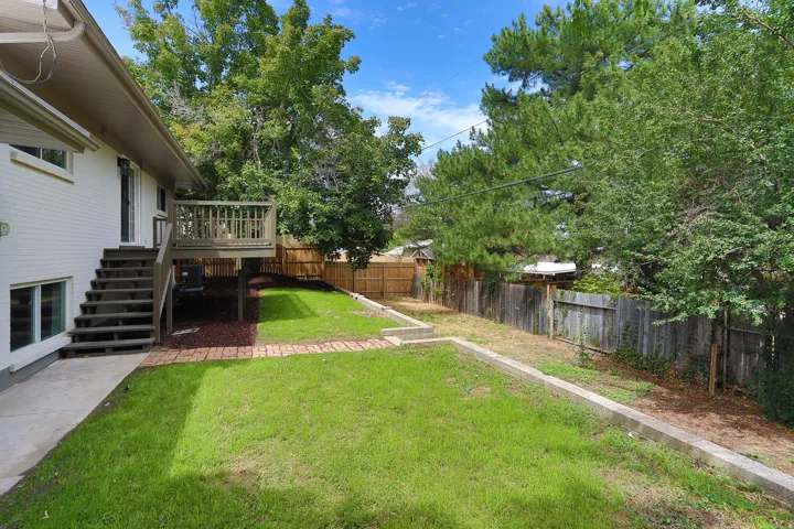 Expansive backyard featuring a tiered lawn, wood privacy fencing, and mature trees